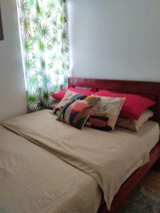 a bed with some pillows on it with a window at Laly's B8 cozy Vacation Townhouse in Olongapo