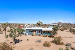 a blue house in the middle of the desert at 2 Homes, Hot Tub, Firepit, BBQ, Games by MariamsBnb in Joshua Tree