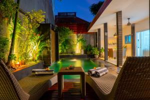 a pool in a backyard with two chairs and a table at Altea Villa Legian - 2BR Private Pool, Prime Location & Walk to Beach in Legian