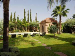 a park with chairs and a building and palm trees at Private Villa at Jardins de Touhina in Marrakesh