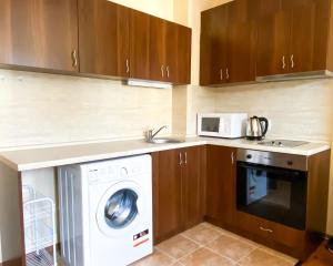 a kitchen with a washing machine and a microwave at "Mountain Dream" Apartments 200m from Ski Road in Bansko