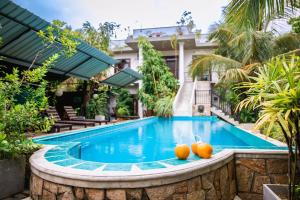 a swimming pool in front of a house with two oranges at Optimum Residencies in Negombo