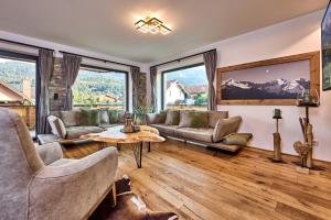 a living room with couches and a table and windows at Apartment Wood&Stone Alpi in Garmisch-Partenkirchen
