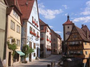 an alley in a town with buildings and a clock tower at Glocke Weingut und Hotel in Rothenburg ob der Tauber