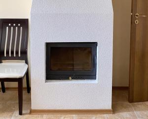 a white wall with a fireplace with a chair at "Mountain Dream" Apartments 200m from Ski Road in Bansko