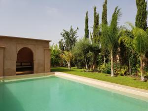 a swimming pool in a yard with palm trees at Private Villa at Jardins de Touhina in Marrakesh