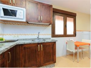 a kitchen with wooden cabinets and a table and a microwave at A 15 minutos Granada, piscina, jacuzzi, barbacoa in Güevéjar