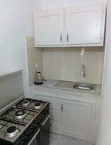 a white kitchen with a stove and white cabinets at Residence le prestige in Kribi
