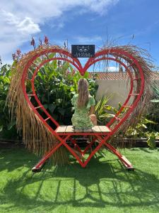 une femme assise dans une grande sculpture cardiaque dans l'établissement love room Villa Des Charmes-34450 vias, à Vias