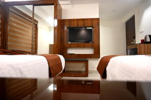 a hotel room with two beds and a flat screen tv at Harley Residency in Kannur
