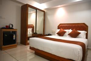 a bedroom with a large bed and a mirror at Harley Residency in Kannur