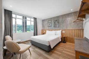 a hotel room with a bed and a chair at The Bayou Hotel Langkawi in Pantai Cenang
