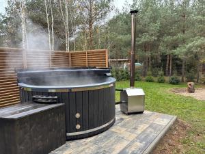 a hot tub and a grill in a yard at Dom Na Brzegu Ciszy in Pasym