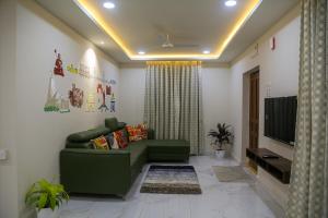 a living room with a green couch and a television at Delightful 3 Bed holiday home with AC Near US Embassy, Gachibowli in Hyderabad