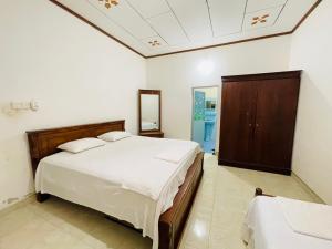 a bedroom with a large white bed and a cabinet at Shalomi's villa & Happy Home in Negombo