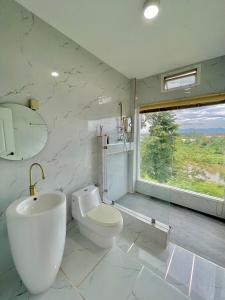 a bathroom with a toilet and a sink and a window at River valley resort แอทน่าน in Nan