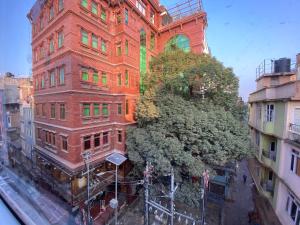 a tall brick building with a tree in front of it at Cozy French studio apartment with balcony in Kathmandu