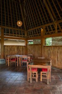 a wooden pavilion with tables and chairs in it at Saridevi Ecolodge in Jatiluwih