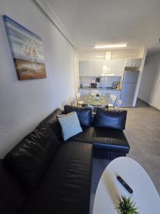 salon z czarną skórzaną kanapą i kuchnią w obiekcie Sunny bungalow La Mata with sea views w mieście Torrevieja