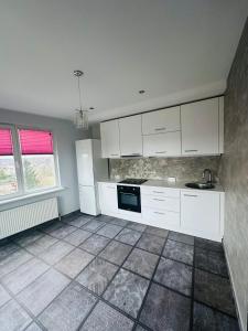 a kitchen with white cabinets and a tile floor at Penthouse in a heart of Adazi in Ādaži +3 photos