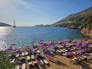 a group of people on a beach with purple umbrellas at Apartments Laus in Dubrovnik