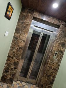 a walk in shower in a bathroom with brown tiles at Pragya international in Varanasi