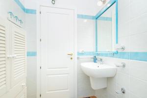 a white bathroom with a sink and a mirror at CASTELSARDO Casa Raoul Piscina e vista mare in Castelsardo