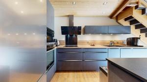 a kitchen with stainless steel appliances and wooden ceilings at Chalet Grand Croix - Haut Standing - 8, 10 pers in Lanslebourg-Mont-Cenis