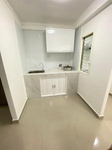 a small white kitchen with a sink and a window at Cozy townhouse near by Klong Dao beach in Ban Mo Nae