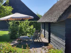 a patio with an umbrella and chairs and a table at Gastenverblijf Lheederhof Lodge 3 in Dwingeloo