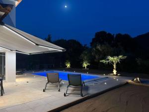 two chairs sitting next to a swimming pool at night at Casamea - Villa Familiale, Piscine, 15 min Ajaccio in Alata