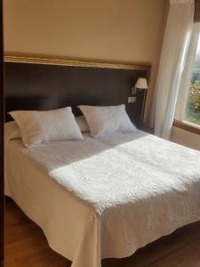 sypialnia z dużym łóżkiem z białą pościelą i oknem w obiekcie Apartamentos Villa Sofía w mieście San Vicente de la Barquera