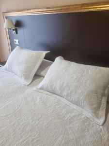 a bed with white sheets and pillows on it at Apartamentos Villa Sofía in San Vicente de la Barquera