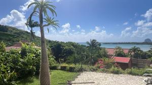 a view of the ocean from a resort with palm trees at Villa Bleue, piscine, vue mer in Le Diamant