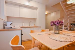 a kitchen with a table with purple flowers in a vase at Dom Na Brzegu Ciszy in Pasym