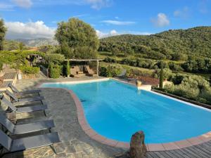 a swimming pool with chairs and a mountain in the background at Auberge U Sirenu in Sartène