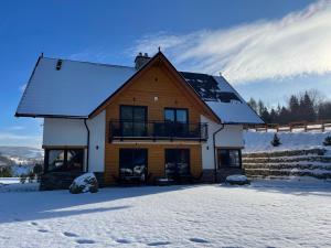 a large wooden house with snow on the ground at Apartament Tatry&Pieniny in Szlachtowa