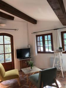 a living room with a tv and two chairs and a table at Mas du ciel en Cévennes in Arphy