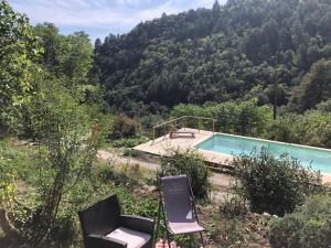 a swimming pool with two chairs next to a mountain at Mas du ciel en Cévennes in Arphy
