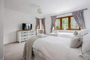 a white bedroom with two beds and a television at Luxury6BedHouse-HotTub-GamesRoom-Amar Luxury Stays in Poole