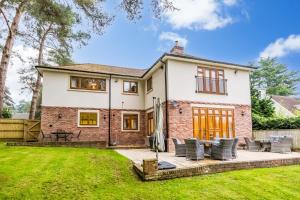 a detached house with a patio and lawn at Luxury6BedHouse-HotTub-GamesRoom-Amar Luxury Stays in Poole