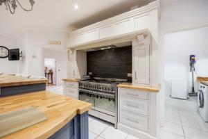 a kitchen with white cabinets and a stove top oven at Luxury6BedHouse-HotTub-GamesRoom-Amar Luxury Stays in Poole