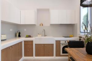 a kitchen with white cabinets and a sink at Aurora House Astypalea B in Pera Gyalos +12 photos