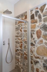 a bathroom with a shower with a stone wall at Aurora House Astypalea B in Pera Gyalos