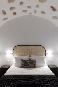 a bedroom with a white bed with a large headboard at Aurora House Astypalea B in Pera Gyalos