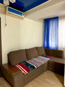 Sofá marrón en una habitación con ventana en Квартира в центре, VEFA, en Bishkek