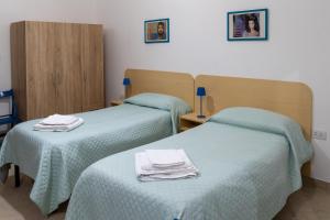 two beds in a hotel room with towels on them at Appartamento per Turisti La Volta 46A in Santa Severina