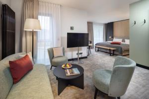 a living room with a couch and chairs and a television at Wellness & Genuss Resort - Engel Obertal in Baiersbronn