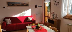 a living room with a red couch and a table at Casarenza a Camporosso in Tarvisio