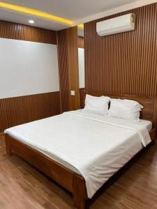 una habitación con una cama grande con sábanas y almohadas blancas en Cherry homestay bmt, en Buôn Ðũng